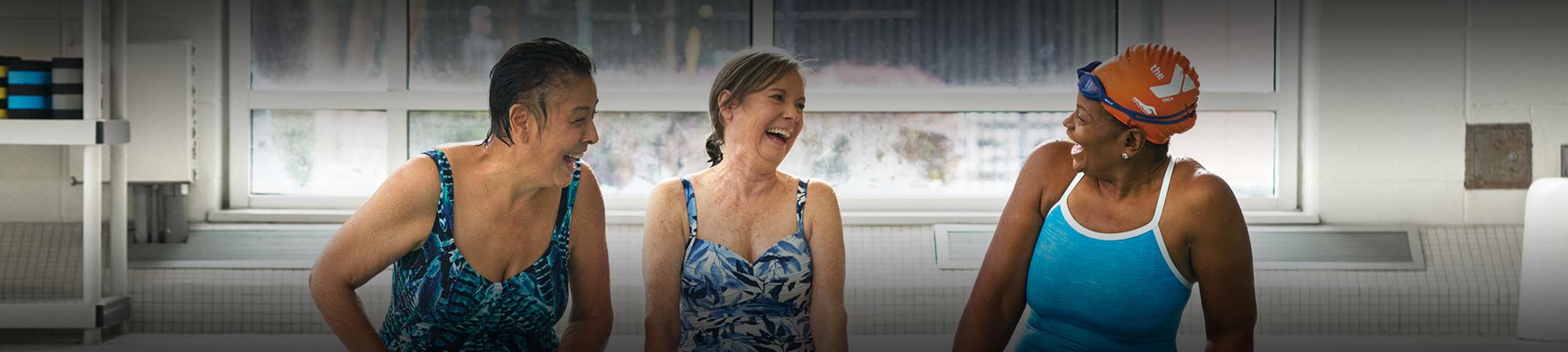 Three women sitting by the pool, laughing